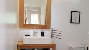 Ein Badezimmer mit einem Holzbadschränken, einer weißen Spüle und einem Spiegel.