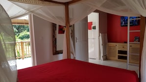Ein Zimmer mit einem Bett, einem Kleiderschrank und einer Tür, die auf einen Balkon führt.