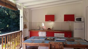 Eine Küche mit einem Holztisch, roten Schränken und einem weißen Kühlschrank.