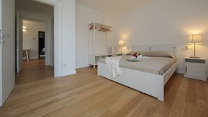 A bedroom with a bed, bedside tables, a wardrobe, and a door leading to another room. - Argegno Home, Argegno, Italy (Argegno)