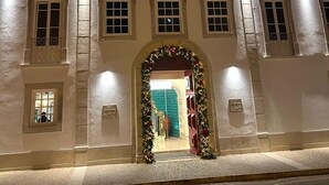 Un bâtiment historique à la façade symétrique, doté de nombreuses fenêtres et d’une entrée centrale agrémentée de décorations festives.