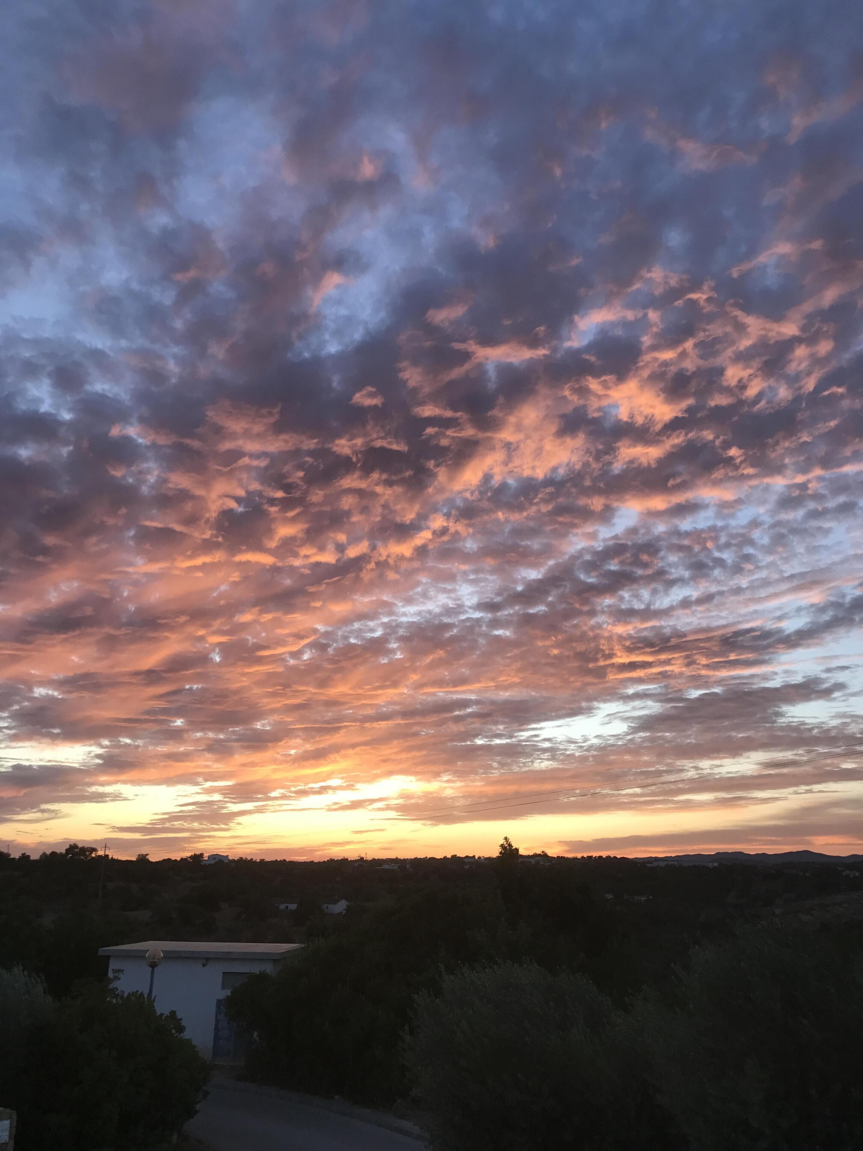 Un coucher de soleil avec un ciel rempli de nuages.