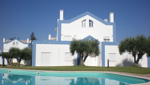 Une maison moderne à deux étages, avec une piscine en premier plan.