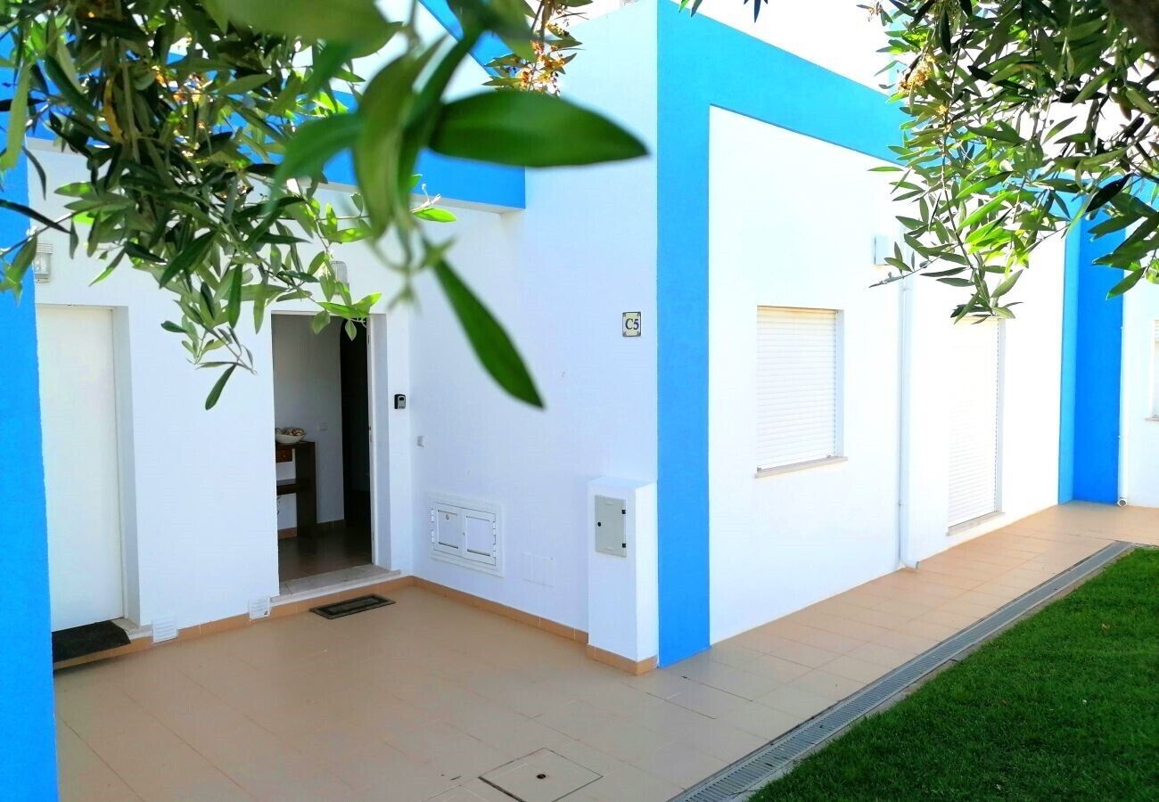 A building with a blue and white exterior, a tiled entrance, and a small grassy area.