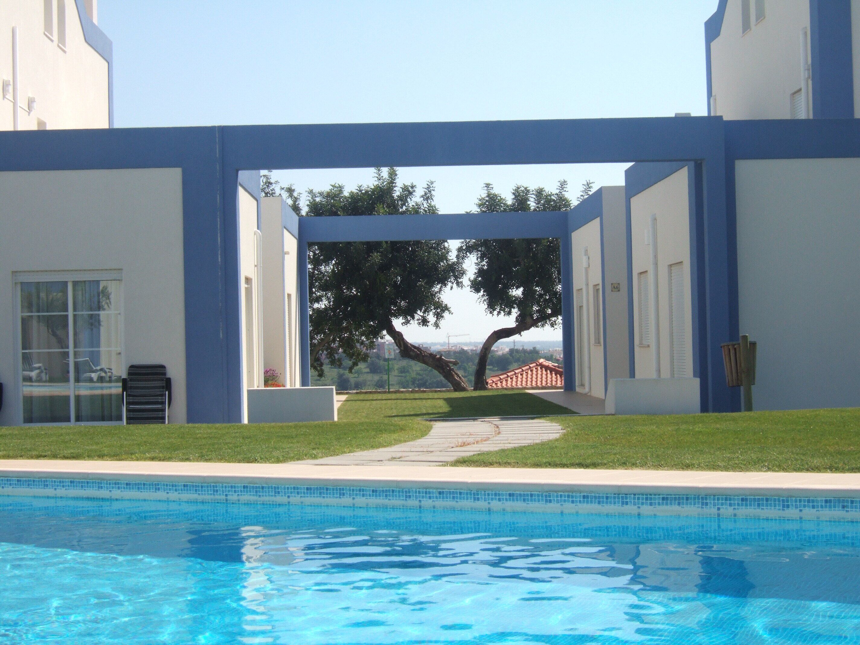 Una piscina con vista su un albero e un paesaggio urbano in lontananza.