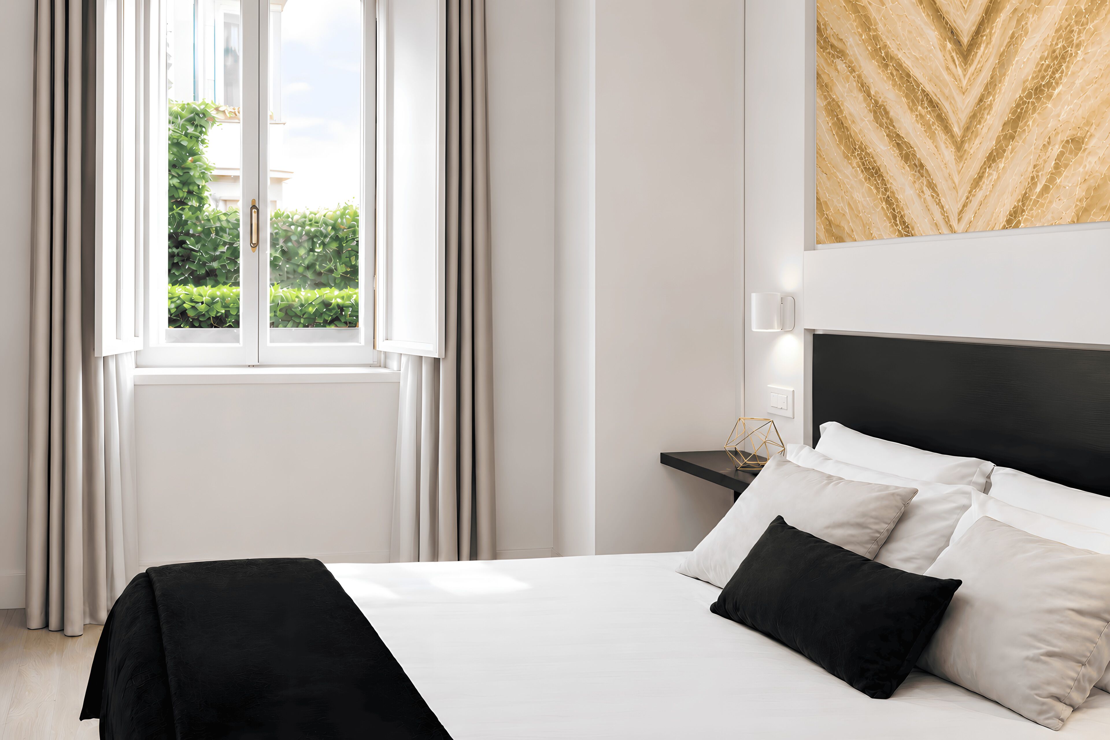 A hotel room with a bed, a nightstand, and a window with curtains.