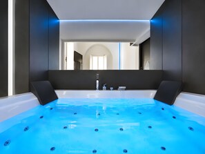 A modern bathroom with a large bathtub, a mirror, and a door leading to another room. - Ultra-Luxury Private Spa Suite at the Spanish Steps (Roma)