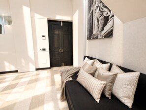 A modern room with a black sofa, beige cushions, a large abstract painting, and a checkered floor.