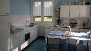 Una cucina compatta con mobili bianchi, un lavello e una finestra vista su un campo verde.