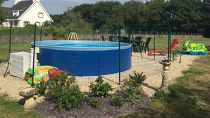 Un cortile con piscina fuori terra blu, circondato da una recinzione.