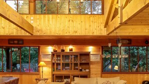 A spacious wooden interior with a high ceiling, a dining area, a sofa, and a table with candles. - Charming house in Cap Ferret with private pool in a haven of peace (Lège-Cap-Ferret)
