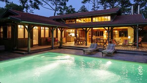 A two-story house with a swimming pool, outdoor seating, and a covered patio area. - Charming house in Cap Ferret with private pool in a haven of peace (Lège-Cap-Ferret)