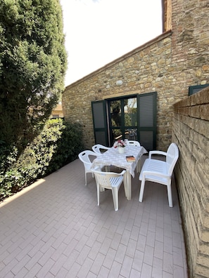 Un patio al aire libre con un muro de piedra, una mesa con sillas y una planta en maceta.