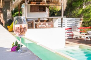 A glass of wine on a poolside table with a pool and lounge chairs in the background. - Splendid Villa with private pool and stunning views in Sperlonga, near Rome (Sperlonga)
