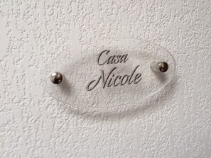 A clear nameplate with the inscription "Casa Nicole" mounted on a textured wall.