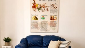 A modern living room with a blue sofa, a white table, and a wall-mounted menu board.