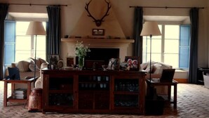 Ein geräumiges Wohnzimmer mit Kamin, zwei Sofas, einem Couchtisch und einem großen Wanddeerhorn.