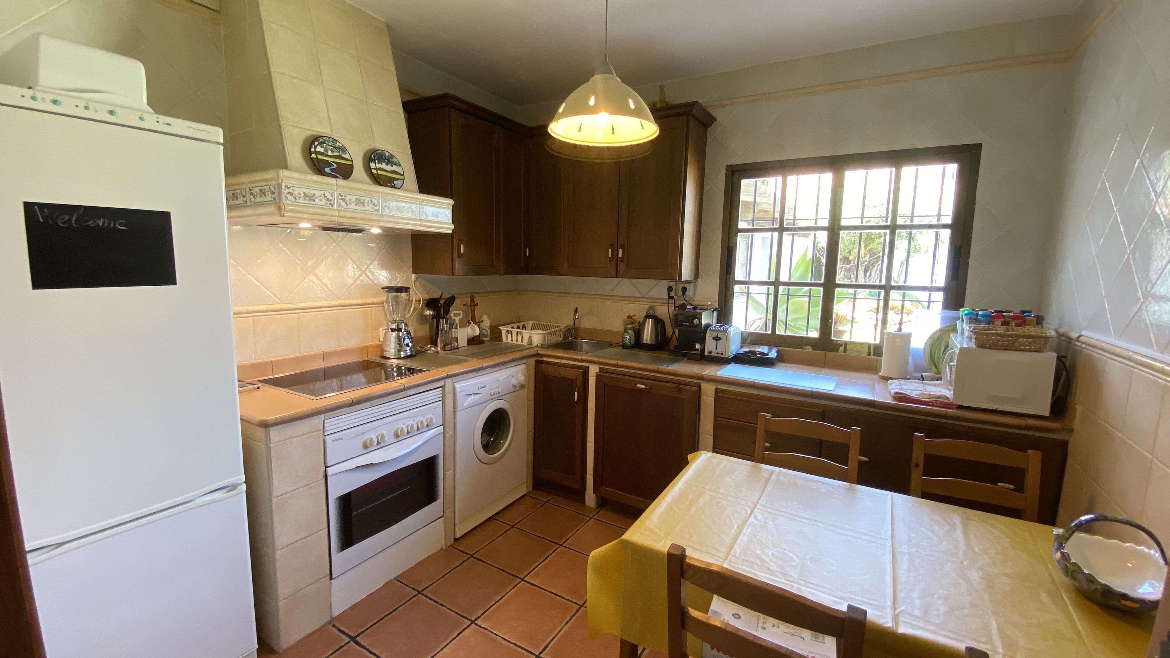 A kitchen with a washing machine, oven, and a table with chairs.