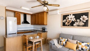 Une cuisine compacte avec des meubles en bois, un réfrigérateur encastré et un coin repas comprenant une table et des chaises.