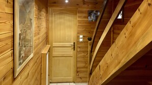 Interior de madera con puerta de madera, una lámpara y un interruptor de luz en la pared.