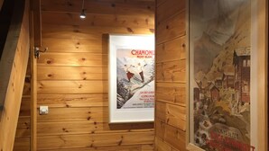 Un pasillo interior de madera con un cartel enmarcado de un paisaje montañoso y un anuncio de un complejo de esquí.