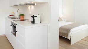 A compact kitchenette with a stove, sink, and a coffee machine. - THE RIVERSIDE SUITE and POOL near VENICE (Mira)