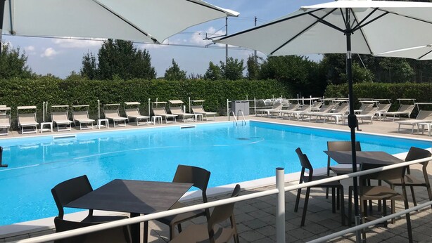 A swimming pool with lounge chairs and umbrellas, surrounded by a hedge. - THE RIVERSIDE SUITE and POOL near VENICE (Mira)