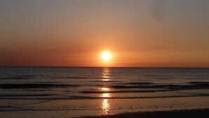 Un coucher de soleil sur l’océan, avec des vagues calmes qui reflètent la lumière du soleil.
