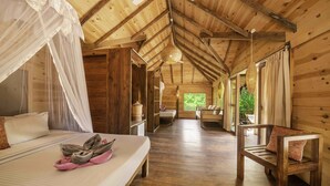 A wooden cabin with a bed, a bench, and a window with curtains.
