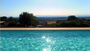 Una piscina con agua cristalina, rodeada de vegetación y vistas a montañas distantes.