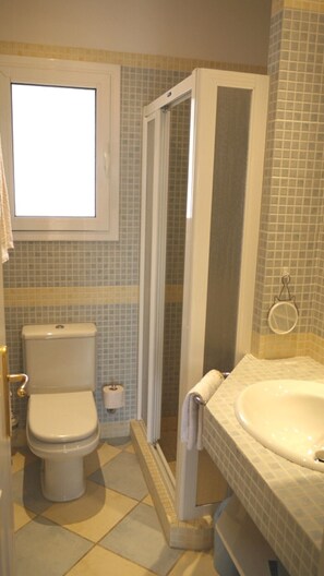 Un baño con inodoro, ducha y lavamanos.
