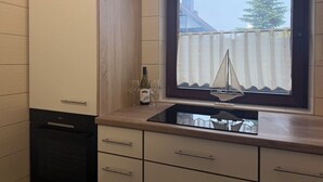 A kitchen with a window, a wine bottle, and two glasses on the counter. - FeWo Seestern... at home on vacation (Büsumer Deichhausen)