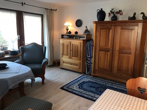A cozy room with a dining table, a chair, a cabinet, and a rug.