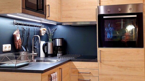 Una cocina moderna con armarios de madera, horno de acero inoxidable y encimera negra.