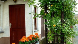 Un edificio con puerta de madera y un jardín de flores de caléndula.