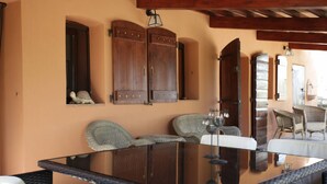 Ein Zimmer mit einem Glastisch, Korbstühlen und Holzschränken.