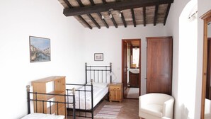 Ein Schlafzimmer mit Bett, Schreibtisch, Stuhl, Kleiderschrank und Deckenventilator.