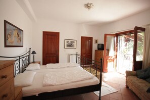 A bedroom with a bed, wooden wardrobe, and a television.