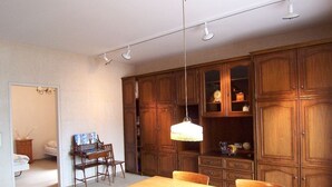 Un coin repas avec une table et des chaises en bois, un lustre et des meubles de rangement en bois.