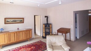 Un salon comprenant un canapé, un meuble en bois, un tapis à motifs, une petite table et un poêle à bois.