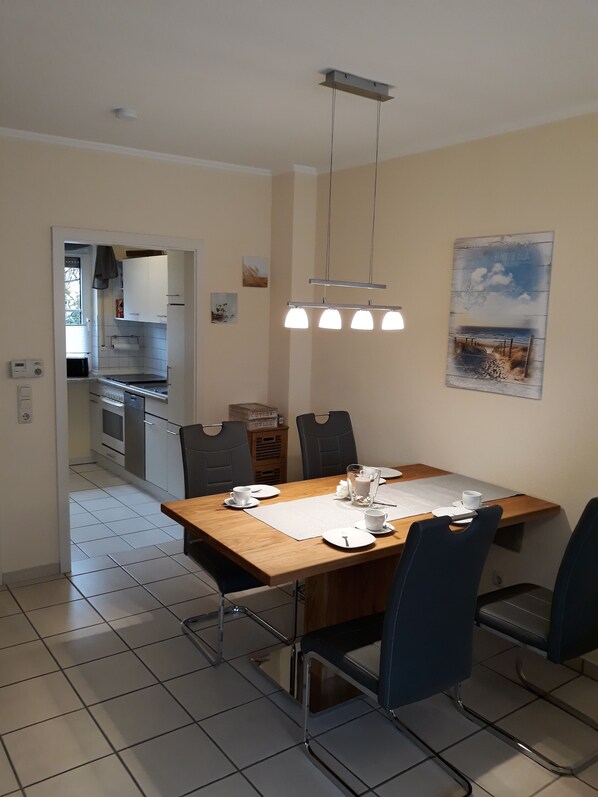 A dining area with a wooden table, four chairs, and a hanging light fixture.