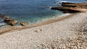 A rocky beach with clear water and distant cliffs.