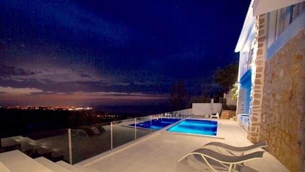 A rooftop pool area with a view of the city at night.