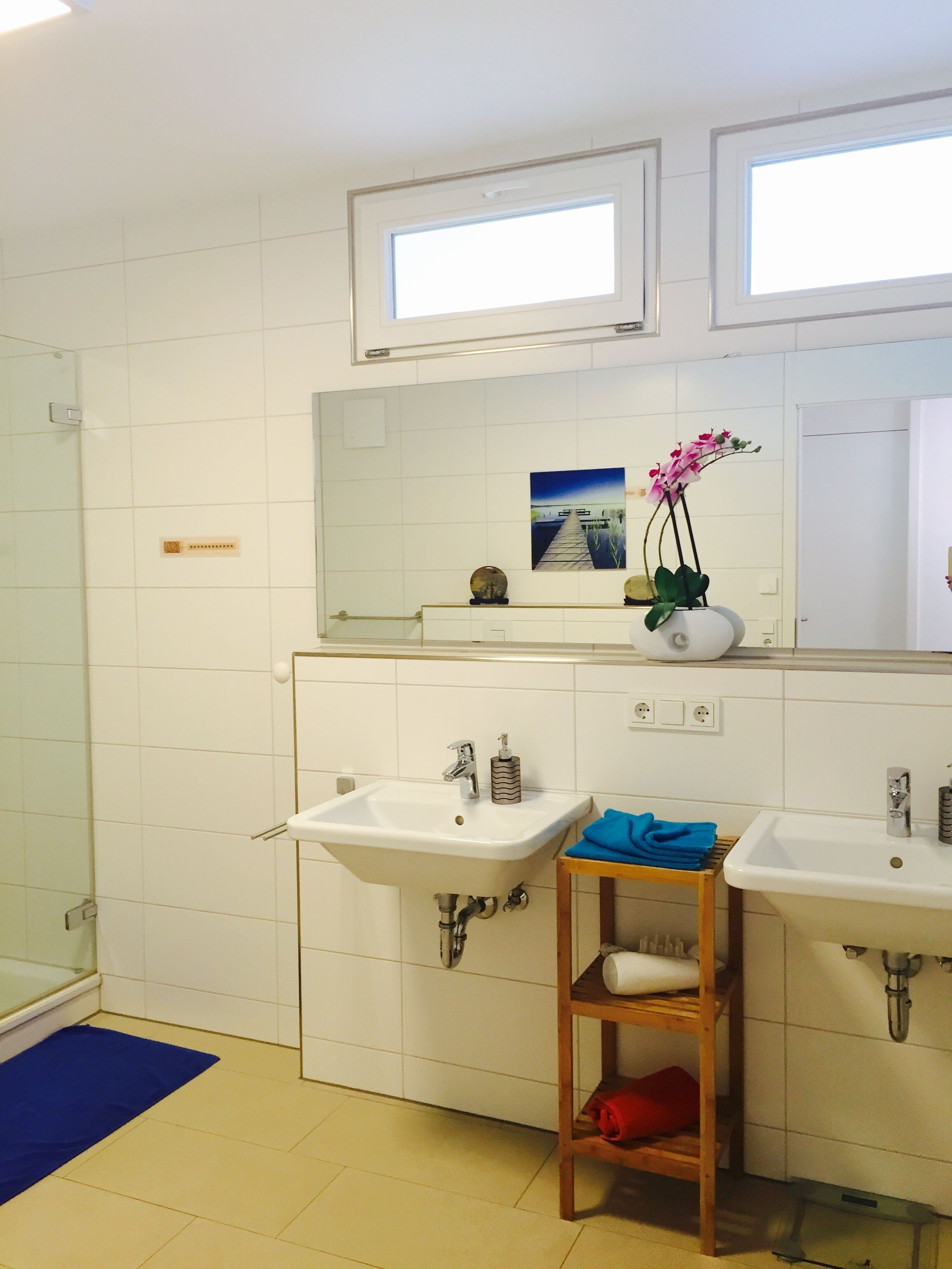 Een badkamer met twee wastafels, een spiegel en een raam.