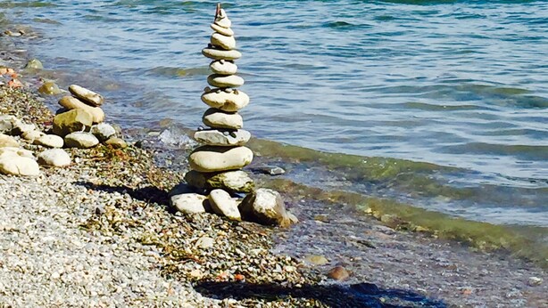A river with a stone cairn in the foreground and a bridge in the background.