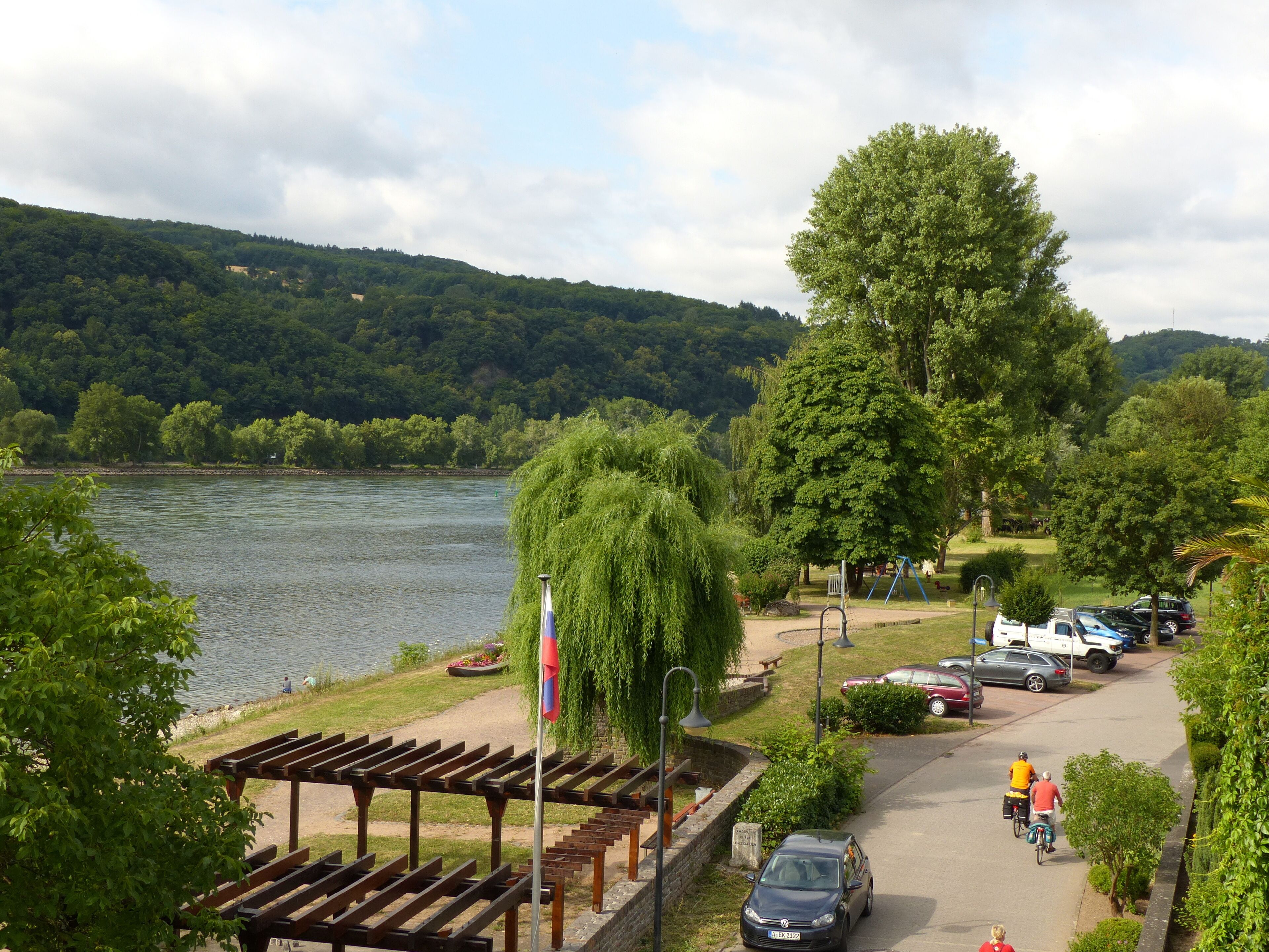 Ein Park am Flussufer mit einem Kiosk, Picknicktischen und einem Spielplatz.