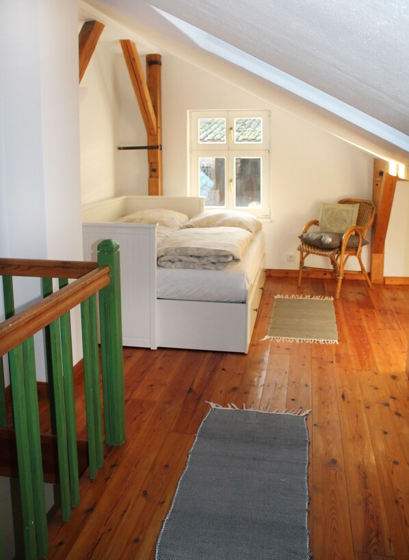 A small, cozy attic bedroom with a single bed, a chair, and a window. - Uckermark old farmhouse with large wild garden (Templin)