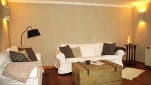 A living room with a white sofa, a white armchair, a wooden chest, and a floor lamp. - Uckermark old farmhouse with large wild garden (Templin)