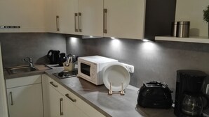 Una cocina moderna con un lavamanos, cafetera, microondas y hervidor.