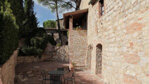 A stone building with a patio area featuring a table and chairs, surrounded by greenery. - Vacation in a former monastery from the 14th century - Loggia apartment (Colle Val Elsa)